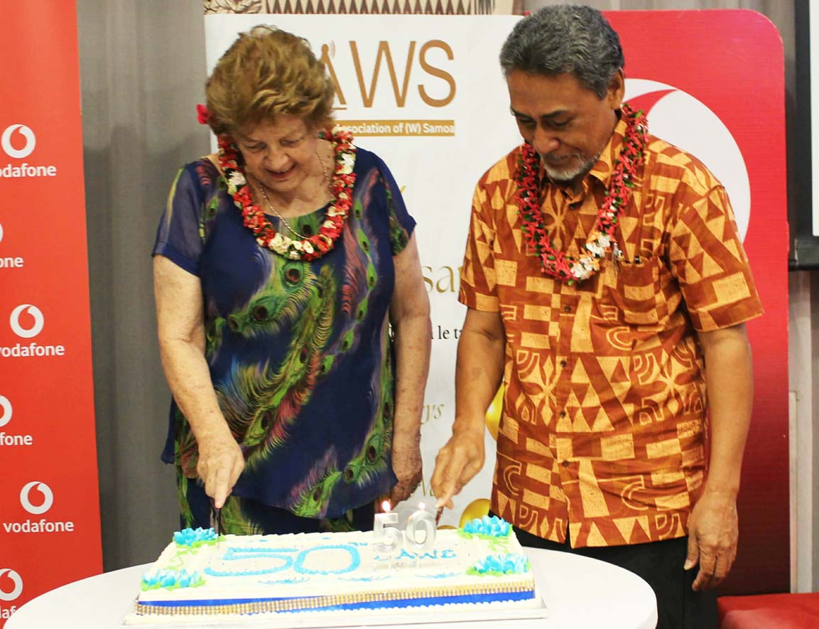 A woman and a man in a JAWS celebration cutting a cake